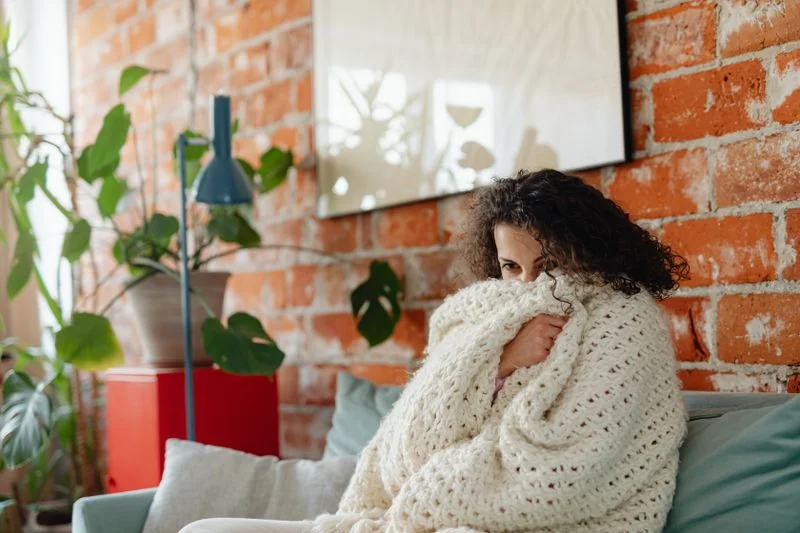 femme qui a froid dans son salon